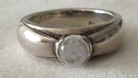 Close-up front view of the sterling silver ring with round moonstone cabochon showing the stone and band thickness.