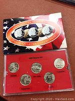 Photo showing one of two 1999 Denver Mint State Quarters sets in red plastic display case with five quarters depicting Delaware, New Jersey, Pennsylvania, Connecticut, and Georgia