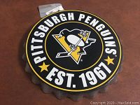 Close-up of the metal sign showing the Pittsburgh Penguins logo with text "PITTSBURGH PENGUINS EST. 1967" and scalloped edges.
