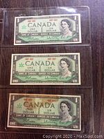 Three Canadian Centennial one dollar bills front side showing Queen Elizabeth II's portrait and bilingual text.