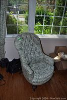 Front view of upholstered chair by window with green toile fabric and button tufting