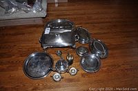 Silver plated tea set, chaffing dish, butter dish, and various trays and serving pieces on a wood floor.