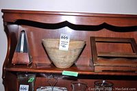 Wooden metronome, turned wood bowl, and wooden book holder displayed on wooden shelf showing overall lot contents.