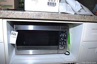 Panasonic microwave oven placed in a kitchen countertop niche with visible stainless steel exterior and black control panel.