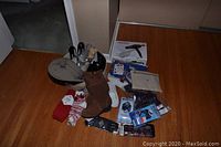 Wide-angle photo of all items including boots, slippers, gloves, hats, hair dryer, bag, and winter traction in packaging on hardwood floor.