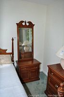 Side table and mirror positioned next to a bed in a room, showing overall size and design.