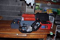 Two toolboxes, Black & Decker mouse sander in case, various hand tools arranged on a wooden table.