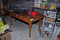 Wood Harvest table with visible wear and scratches, rectangular shape, turned legs, and single drawer.