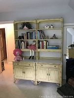 Front view of both yellow bamboo Thomasville bookcase cabinets with decor items displayed