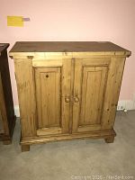 Front view of the larger wood cabinet chest with two doors and wooden knobs.