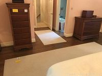 Large neutral ivory area rug with subtle stripes placed on hardwood floor, extending under bed and furniture.