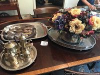 Wide view showing coffee set, trays, serving utensils, and floral urn on dining table.