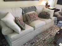Front view of Henredon sofa with three loose cushions and five decorative throw pillows arranged on seat and backrest.