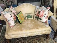 Front view of yellow damask settee sofa with decorative pillows.