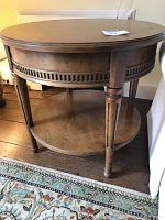 Front angle view showing full round side table with carved apron and lower shelf
