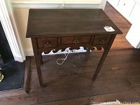 Front view showing rectangular top, three drawers, scalloped apron, and hardware