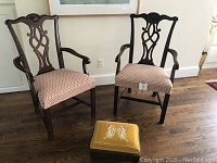 Front view of two chairs and footstool on hardwood floor.