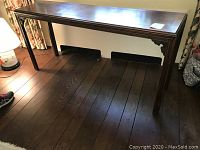 Front-left view of entire console table showing top surface and leg detail