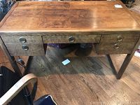 Front view of desk showing five drawers, burl veneer top and brass ring pulls