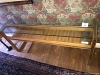 Front view of console table showing clear glass top and wooden lower shelf
