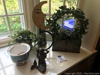 Overview of lot with metal sculptures, planters, and ceramic pot on window ledge.