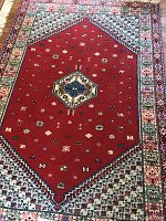 Full view of Moroccan area rug showing central red field, geometric border, and fringe