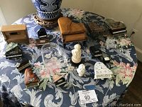 Overview of miniature piano collection and piano-related figurines on floral cloth-covered table, including Limoges boxes and music boxes