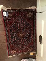 Red Oriental rug with navy central hexagonal medallion and fringed ends