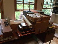 Stacked cardboard boxes, poster tube, plastic crate and books on a table