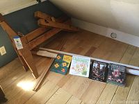 Wooden quilting frame rails and legs laid out on the floor with 3 quilting books arranged in front.