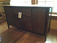 Front view of vintage mid-century buffet showing four drawers and one cabinet door with dark wood finish and round pulls.