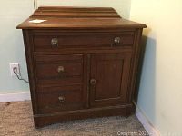 Front view of antique wooden side table showing top, drawers, cabinet door, and metal ring pull knobs.