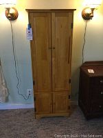 Front view of the pine cupboard with closed doors showing wooden knobs and natural pine finish.