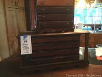 Photo showing both jewelry chests stacked, view of side and front, highlighting size, worn wooden finish, and drawer pulls.