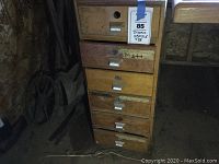 Front of wooden drawer cabinet showing six drawers stacked vertically with metal handles and patina.