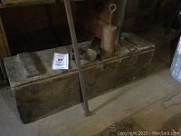 Wooden toolbox on floor filled with metal tools against wooden wall