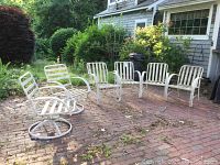 Full set of 6 white metal patio chairs arranged on brick patio, including 2 swivel rocking chairs and 4 armless chairs.