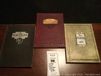 Photo of three hardcover Eastern Nazarene College yearbooks from 1926, 1928, and 1930 placed on a wooden surface showing the front covers.