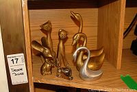 All brass animal figurines displayed together on wooden shelf.