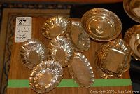 Overview of nine sterling silver small dishes on wood table marked with green tape.