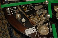 Overview of assorted sterling silver pieces including shakers, spoons, forks, bowls, and servers spread on table
