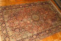 Smaller pink and beige patterned area rug with floral designs, wear and fringe