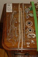 Wood-top table displaying multiple sterling silver chain necklaces on left and brooches on right
