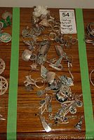 Overhead view showing assorted sterling silver rings, brooches, earrings and accessories arranged within green tape border