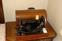 Singer sewing machine set on wooden table with original wooden carrying case in the background