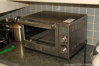 Frigidaire toaster oven on countertop with stainless steel exterior and control knobs on the right side.