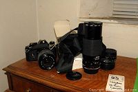 Overview of Nikon EM camera with attached lens, Sigma zoom, additional lenses and strap on dresser