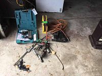 View of all power nailers and pneumatic tools laid on workshop floor including blue Makita case and attached air hoses