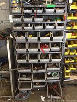 Full view of gray metal shelving unit with multiple plastic bins filled with assorted tools and hardware