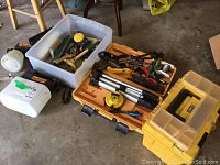 Wagner cordless power paint roller, yellow toolbox with hand tools, white paint supply bin, and tripod sprayer laid out on concrete floor.